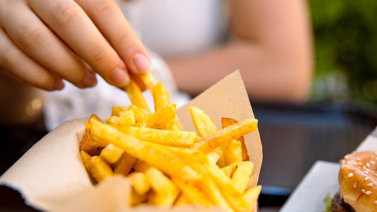 A person eats French fries.