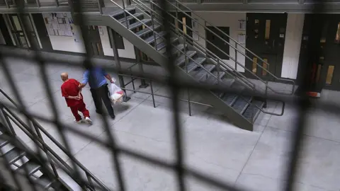 Getty Images A guard escorts an immigrant detainee from his 'segregation cell' back into the general population at the Adelanto Detention Facility on November 15, 2013 in Adelanto, California.