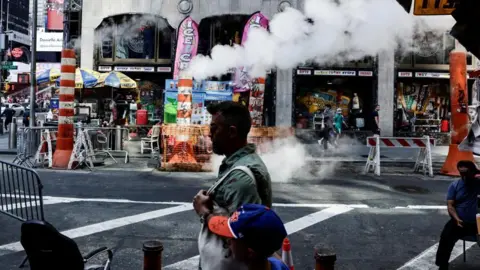 Reuters A man and oy walk past steaming pavement in New York City with stores advertising ice