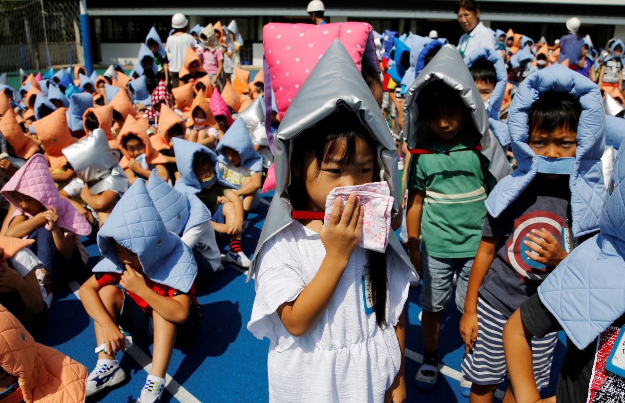 School children wearing padded hoods to protect them from falling debris, take part in an earthquake simulation drill at an elementary school in Tokyo on August 31, 2018.