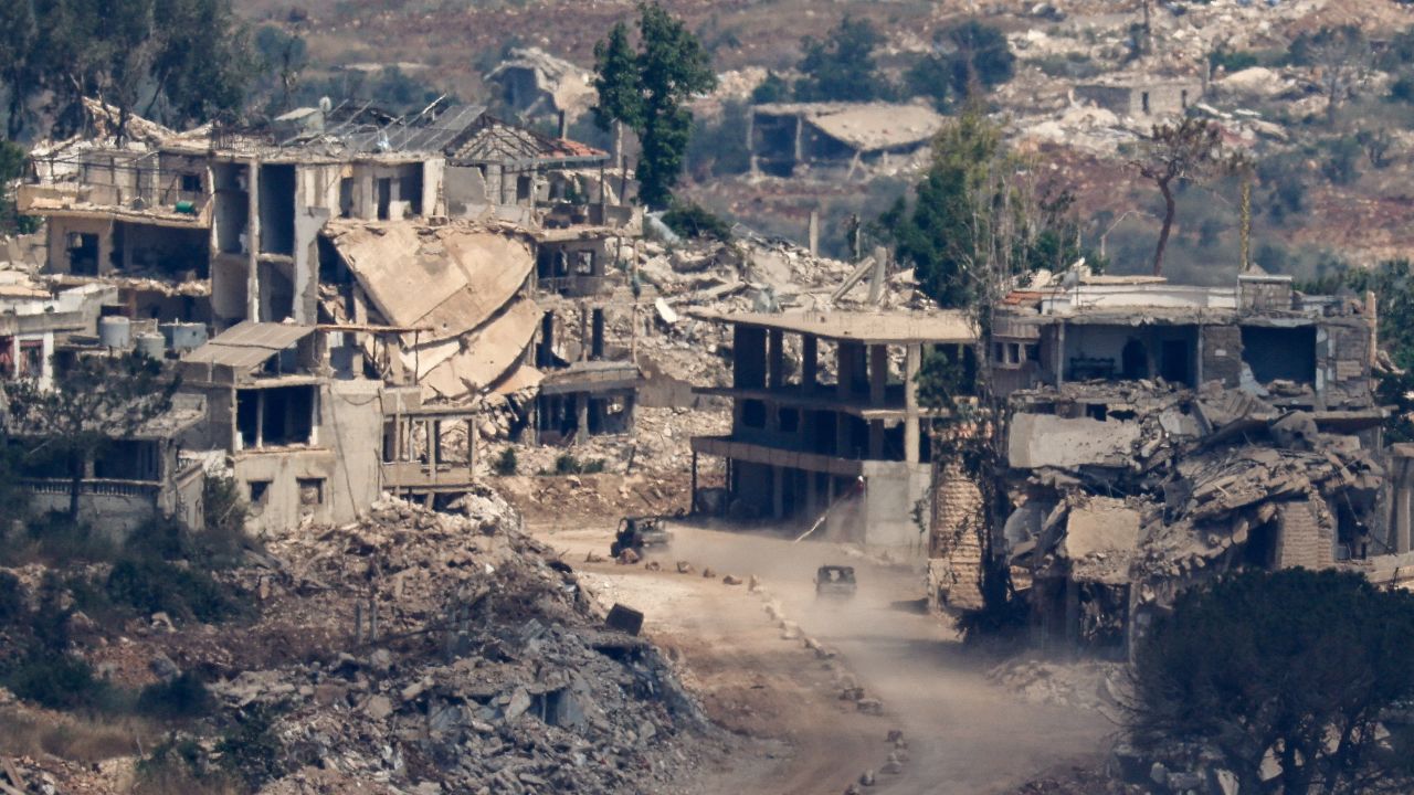 Israeli military vehicles drive amid destroyed buildings in Lebanon on June 27.