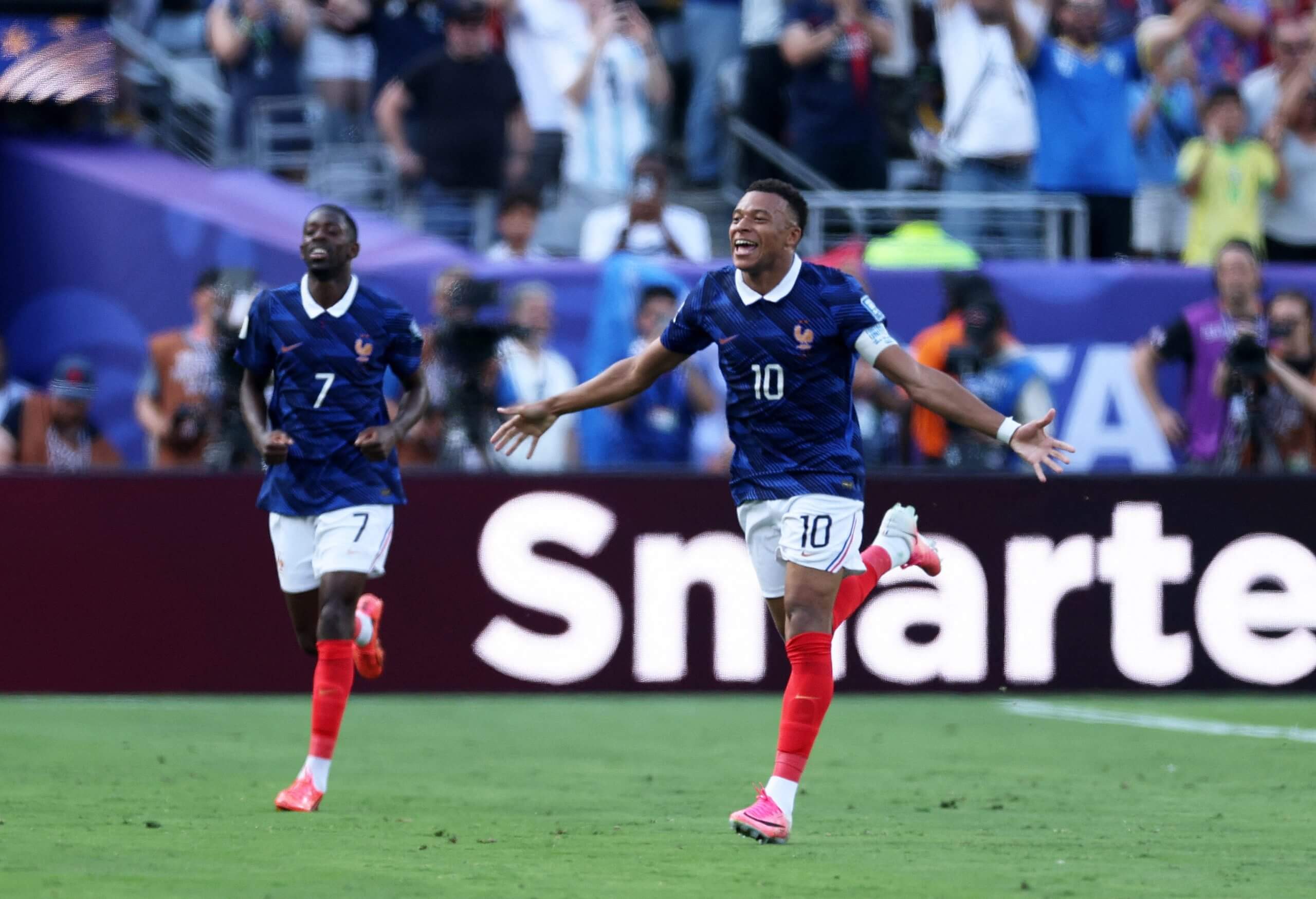 France's Kylian Mbappe celebrates his with his arms outstretched after scoring against Sweden, with team-mate Ousmane Dembele close behind