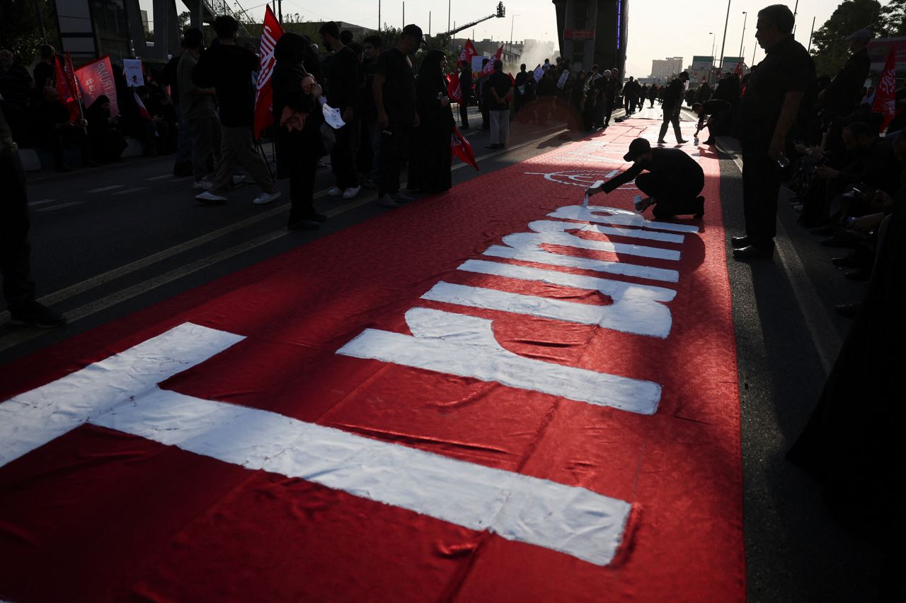A person paints the name of US President Donald Trump on a banner.