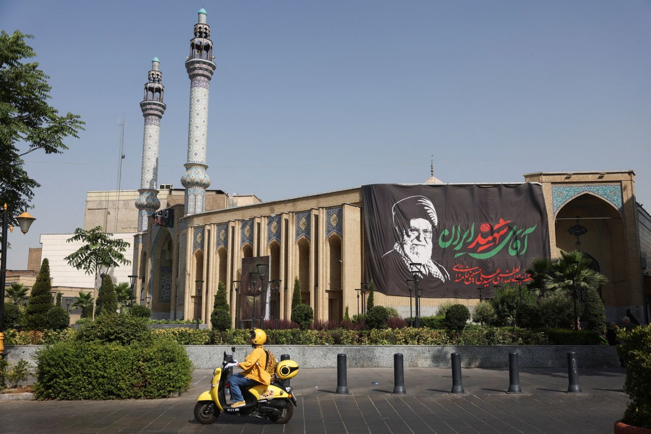 An Iranian woman rides a motorcycle past a banner depicting the late Iranian Supreme Leader Ayatollah Ali Khamenei on a street in Tehran on Sunday.