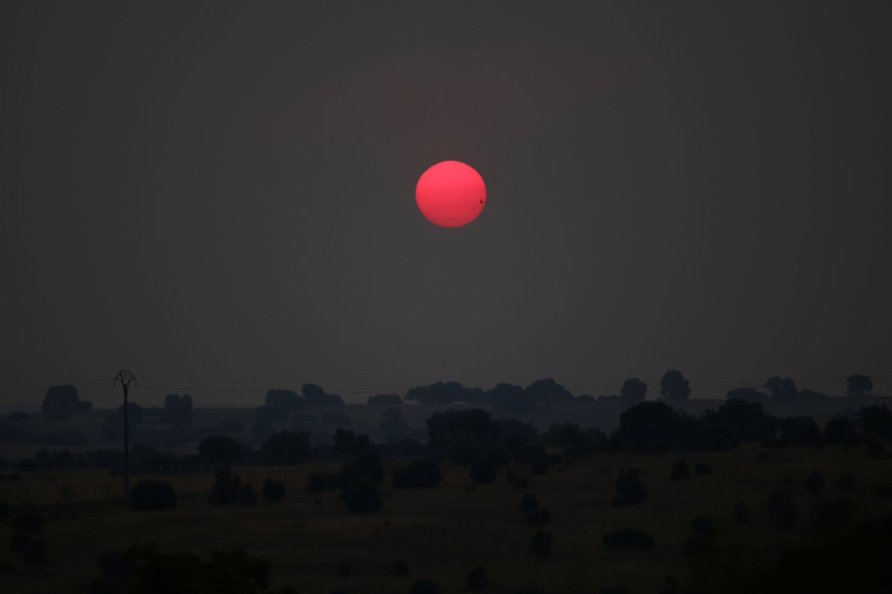 The sun rises behind the smoke of a wildfire in Escalona, Spain.