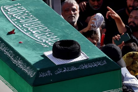 A coffin passes the faces of mourners