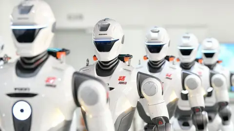 VCG via Getty Images A row of humanoid robots are on display after rolling off the production line at a production facility in China