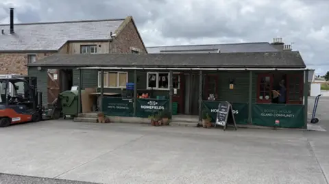 Homefields A shed-style shop, in dark green colour with Homefields branding on the front.