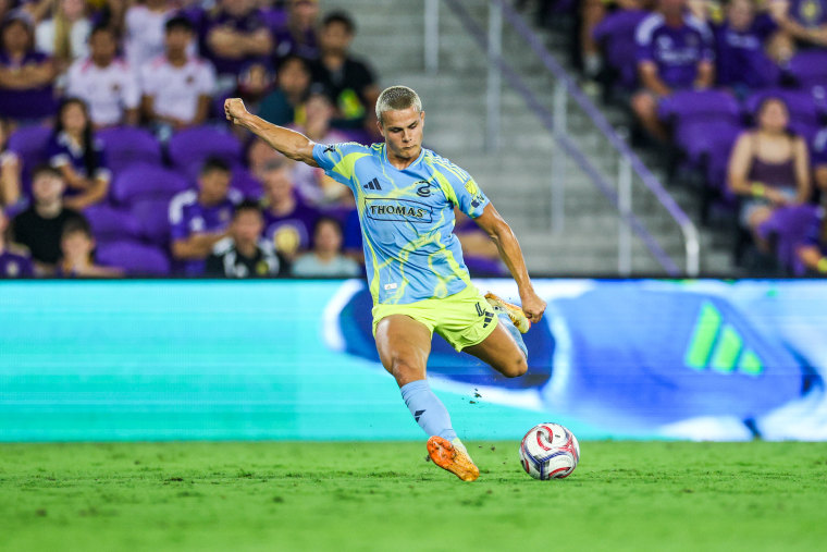 Cavan Sullivan in the middle of kicking a soccer ball on the field