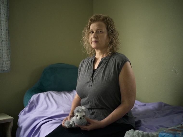 Elyse Thorpe sits on May's bed holding a stuffed animal loved by May.