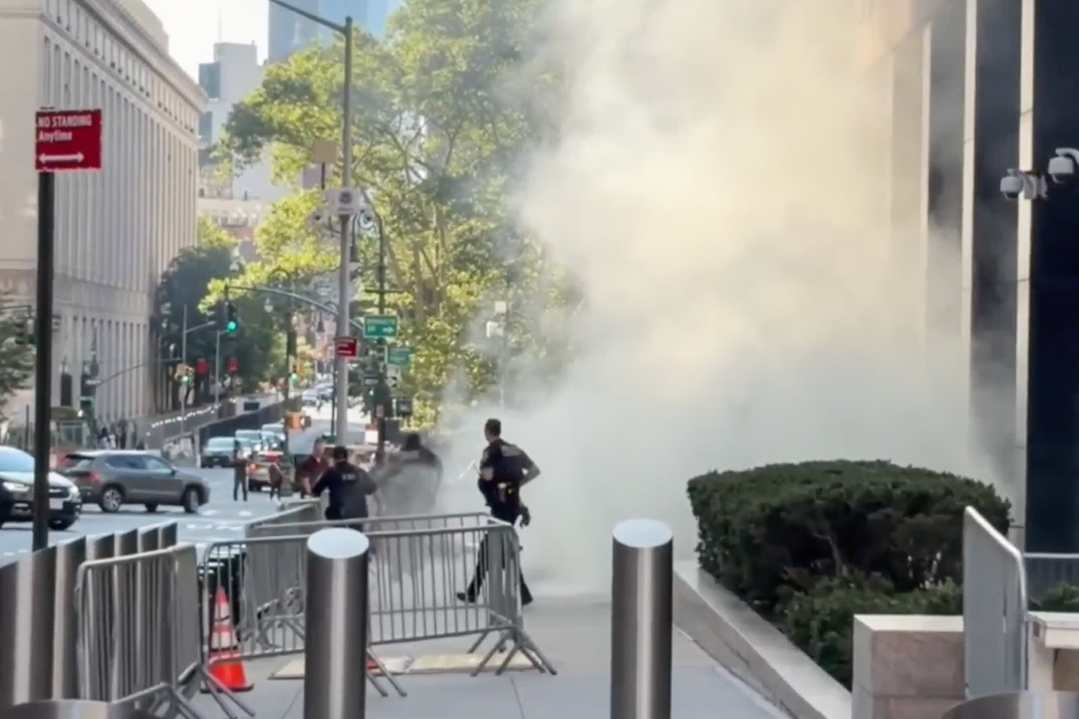 Smoke billows outside as police officers walk outside on a sidewalk