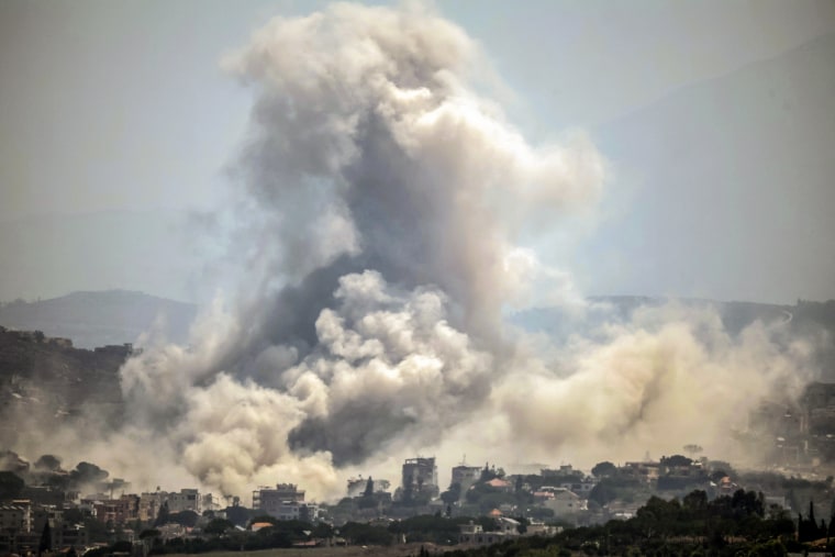 A huge plume of smoke rising into the air above a city skyline.