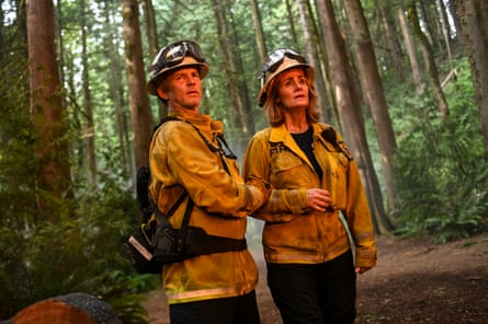 Two people in a forest wearing protective yellow fire outfits