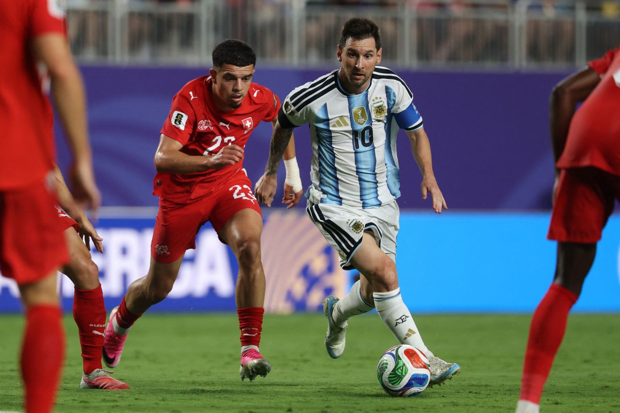 Argentina's Lionel Messi runs with the ball followed by Switzerland's Zeki Amdouni.