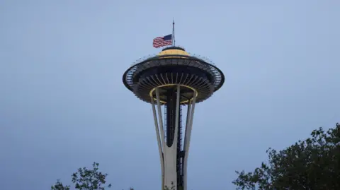 Reuters The Seattle Space Needle building on a twilight background. A large US flag is flying at half-mast as a tribute to the shooting victims.