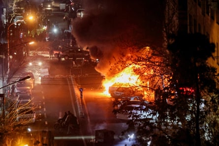 Cars on fire in a Tehran street at night-time.