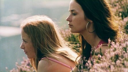 Profiles of two women with long hair, next to a flowery grass, looking into the distance