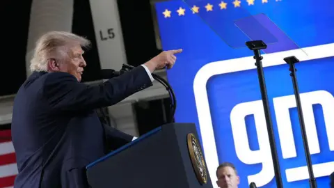 Getty Images Donald Trump speaking in front of a General Motors sign.