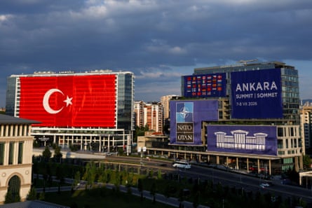 A huge Turkish flag draped over one large building, beside another block decorated with the Nato logo, smaller national flags and the words ‘Ankara summit’