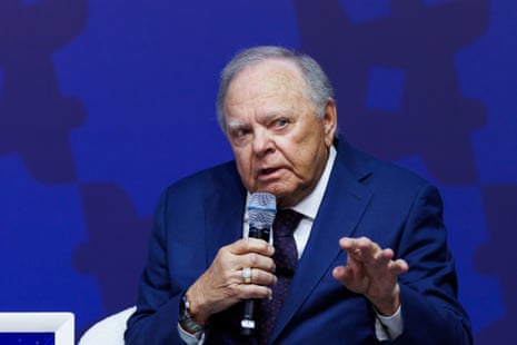 a man in a suit speaks into a microphone while seated