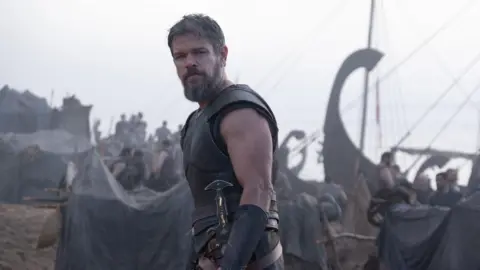 Universal Pictures Matt Damon looking to camera in armour, ships and warriors in background