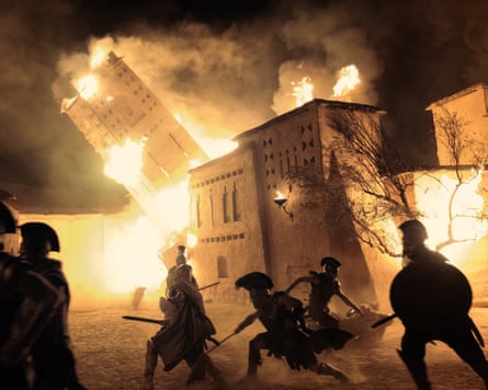 A scene from The Odyssey showing buildings on fire and collapsing