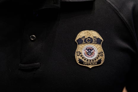 An embroidered ICE officer badge patch on a black polo shirt