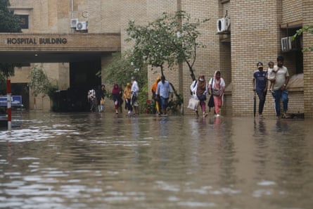 People walk in flooded streets next to hospital building