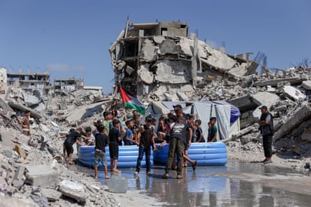 Palestinian children in inflatable pools set up amid the rubble of destroyed buildings