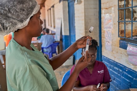 A medical worker checks a syringe of drugs.