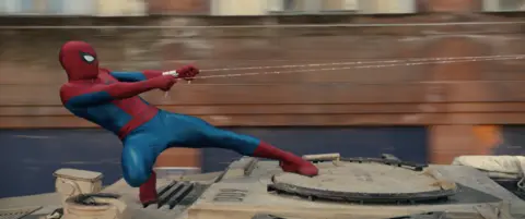 Marvel/Sony Pictures Entertainment Spider-Man standing on top of tank and grabbing on to his web.