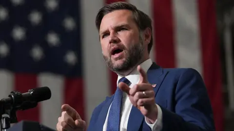 AFP via Getty Images JD Vance wearing a suit and speaking into a microphone in front of an American flag
