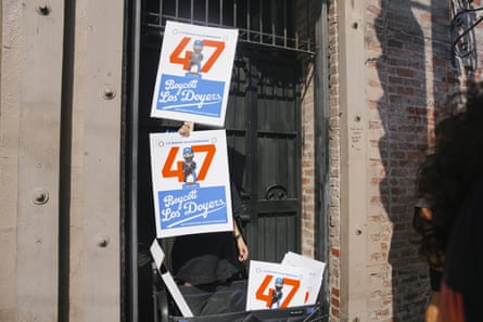 a person holds signs that read ‘boycott the dodgers’
