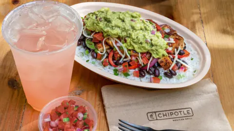 Chipotle A chicken bowl from Chipotle with a drink and a dip.