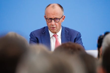 Friedrich Merz speaks to the press, seen from a journalist’s eye view behind rows of heads
