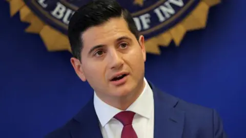 Reuters United States Attorney Bill Essayli stands in front of an FBI logo