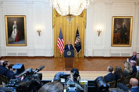 a man in a suit speaks into a microphone in a room
