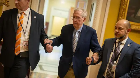 Getty Images McConnell holding the hands of two men on either side of him for support
