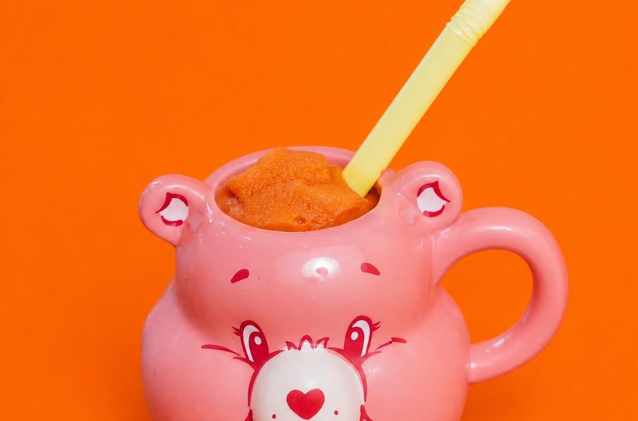 A cute mug in the shape of a pink cartoon bear with a straw.