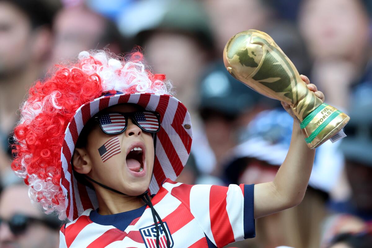 A young U.S. fan holds a miniature replica of the World Cup during the U.S.-Belgium match.