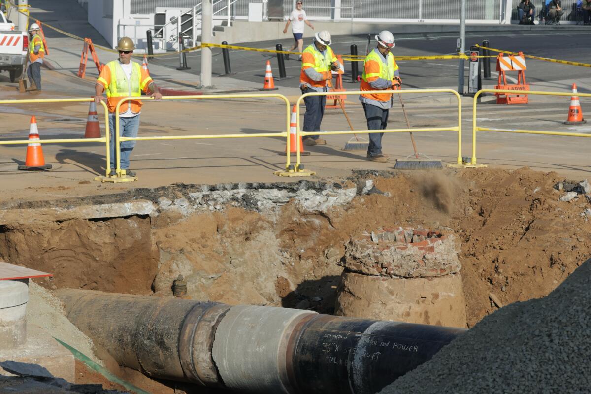 Workers sweep the street over the side to a water main rupture