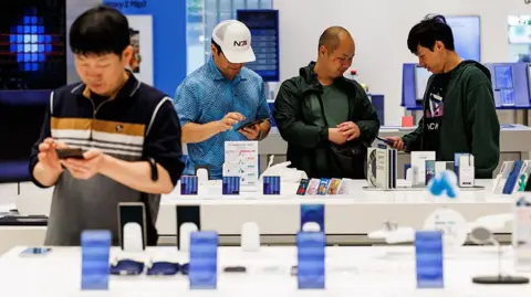 Bloomberg via Getty Images Customers try Samsung smartphones at one of the company's stores in Seoul