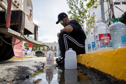 A man filling water containers from a tanker truck
