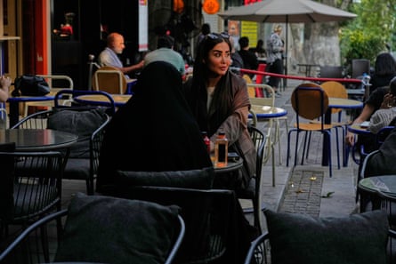 Two women sit at an outdoors table at a cafe in northern Tehran.