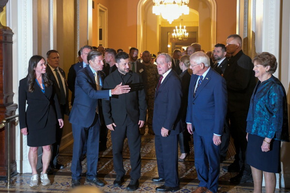 Ukraine President Volodymyr Zelenskyy, center, is joined by from left: Sen. Katie Boyd Britt, R-Ala., Sen. Richard Blumenthal, D-Conn., Sen. James Risch, R-Idaho, Sen. Roger Wicker, R-Miss., and Sen. Jeanne Shaheen, D-N.H., as he arrives at the U.S. Capitol for a meeting of bipartisan leaders of the Lindsey O. Graham Sanctioning Russia and Iran Act of 2026, Tuesday, July 28, 2026, in Washington. (AP Photo/Rod Lamkey, Jr.)