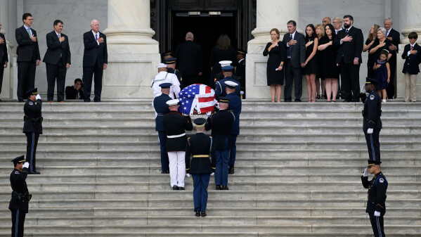 The flag-draped casket of Sen. Lindsey Graham of South Carolina, arrives at the U.S. Capitol, Tuesday, July 28, 2026, in Washington, as his sister, Sen. Darline Graham, R-S.C., top right, and other family members, look on. (AP Photo/Rod Lamkey, Jr.)