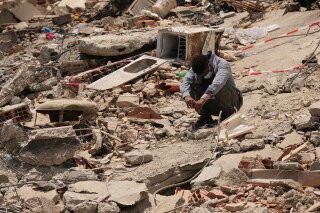 A man sits amid earthquake rubble in La Guaira, Venezuela, June 29, 2026. (AP Photo/Matias Delacroix, File)