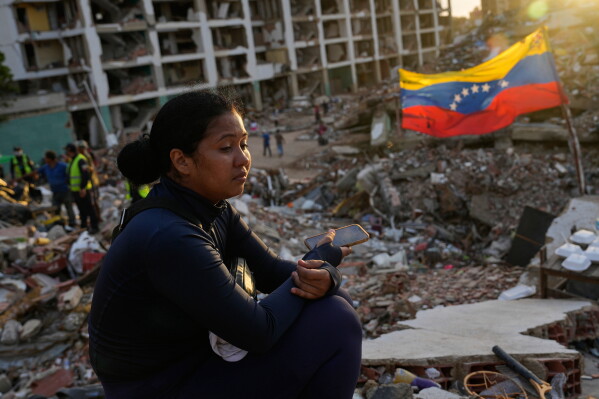 Estefany Landaez sits amid the rubble of a building, waiting to find her two children after the earthquakes in La Guaira, Venezuela, Sunday, July 12, 2026. (AP Photo/Ariana Cubillos)