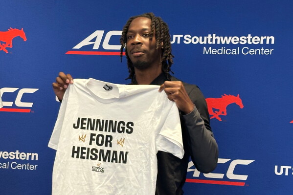 SMU football quarterback Kevin Jennings holds up a T-shirt that is part of the school's Heisman Trophy campaign in Dallas, Wednesday, July 15,2026. (AP Photos/Stephen Hawkins)