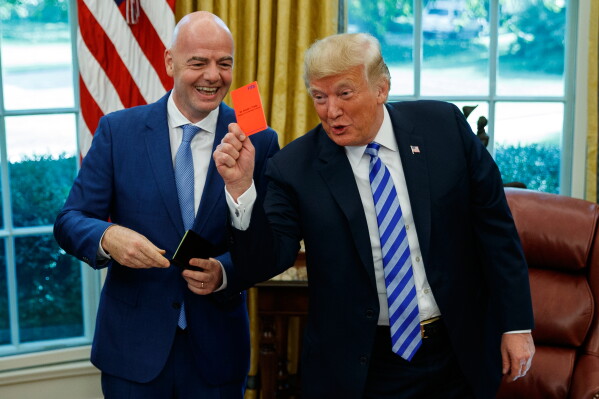 President Donald Trump holds up a red card during a meeting with FIFA president Gianni Infantino in the Oval Office of the White House, Tuesday, Aug. 28, 2018, in Washington. (AP Photo/Evan Vucci, File)
